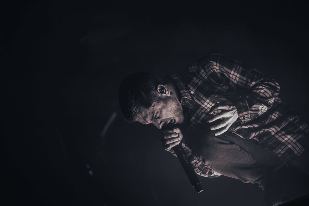 A dramatic black and white photo of Phil Bozeman screaming into a mic.