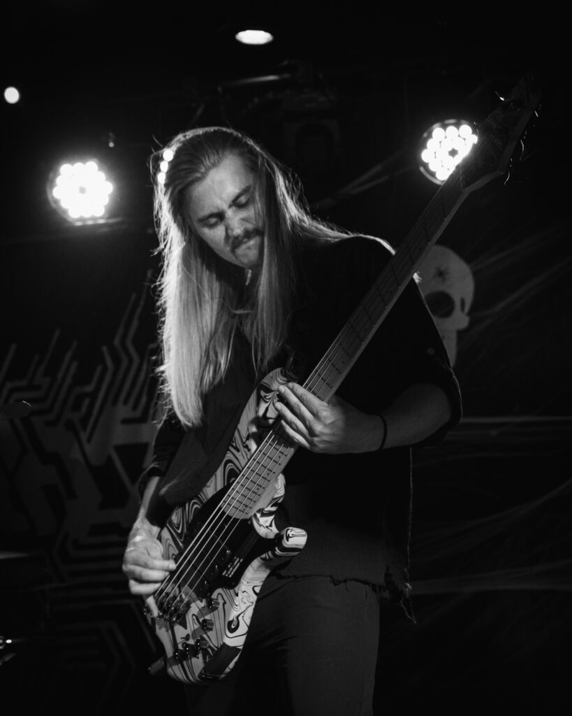 A black and white photograph of an aggressive metal bassist.